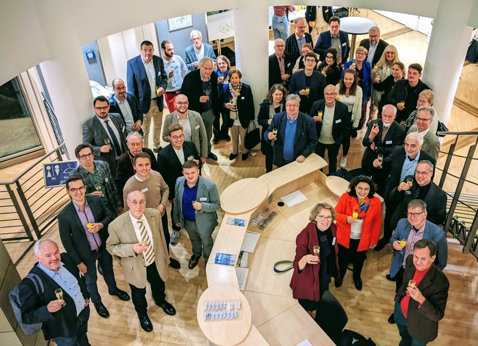 Menschen prosten im Foyer des Tagungsorts Richtung Kamera.